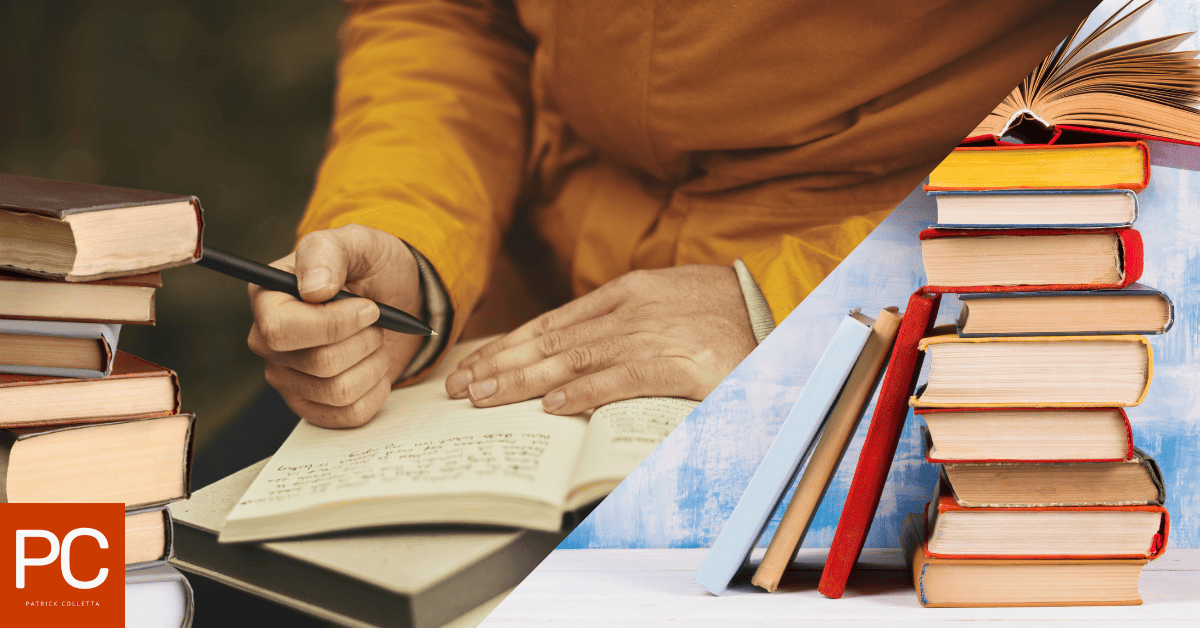 A man writing in his journal surrounded by stacks of books on both sides of him.